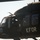 New SACEUR makes first visit to Kosovo A military helicopter marked with 'KFOR' (Kosovo Force) is captured in close-up, showing the cockpit and fuselage. The aircraft appears to be a UH-60 Black Hawk type helicopter painted in olive drab/dark green military livery. At least one crew member is visible through the cockpit windows wearing flight gear.