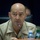 New SACEUR makes first visit to Kosovo A bald male military officer in a tan/khaki uniform is seated at a conference table speaking into a microphone. He wears four-star insignia on both collar points, indicating the rank of Admiral or General. A nameplate and water bottles are visible on the table in front of him.