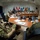 New SACEUR makes first visit to Kosovo A multinational military briefing or conference is taking place in a formal meeting room. Multiple military personnel in various national uniforms are seated around a large conference table. A projection screen displaying 'KOSOVO FORCE' and a map is visible in the background, indicating this is a KFOR (NATO Kosovo Force) meeting.