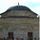 New SACEUR makes first visit to Kosovo A group of multinational military personnel and civilians are walking away from a historic Ottoman-style stone building with a characteristic dome and finial. The group includes uniformed soldiers wearing green berets and camouflage uniforms from what appear to be multiple nations, along with at least one naval officer in tan uniform. The setting appears to be a formal visit or inspection at a historic religious or administrative site paved with stone.