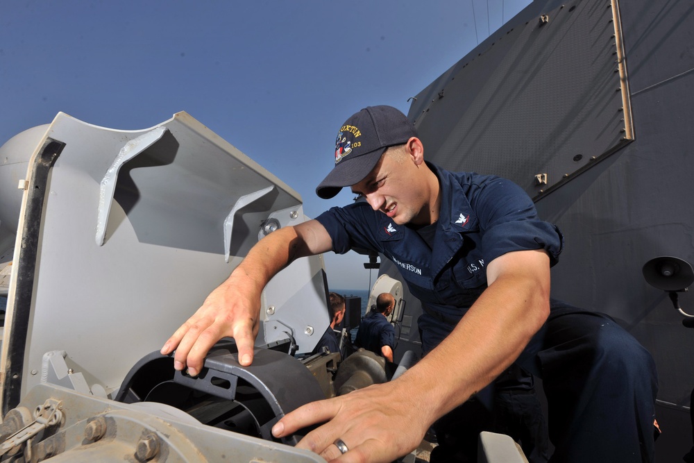 USS Truxtun sailor performs maintenance on machine gun
