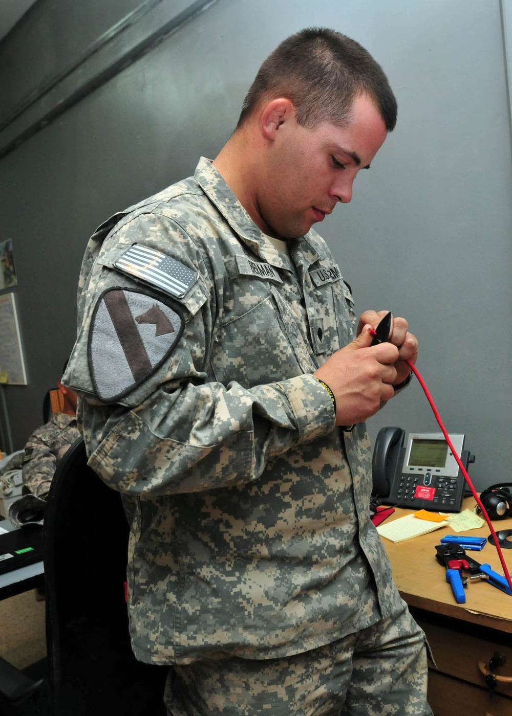 Communications soldier fixes phone cable