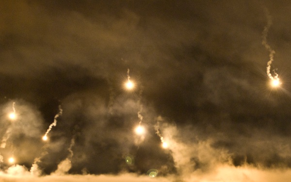 Flares parachute and illuminate the Department of the Army Best Warrior Night Fire