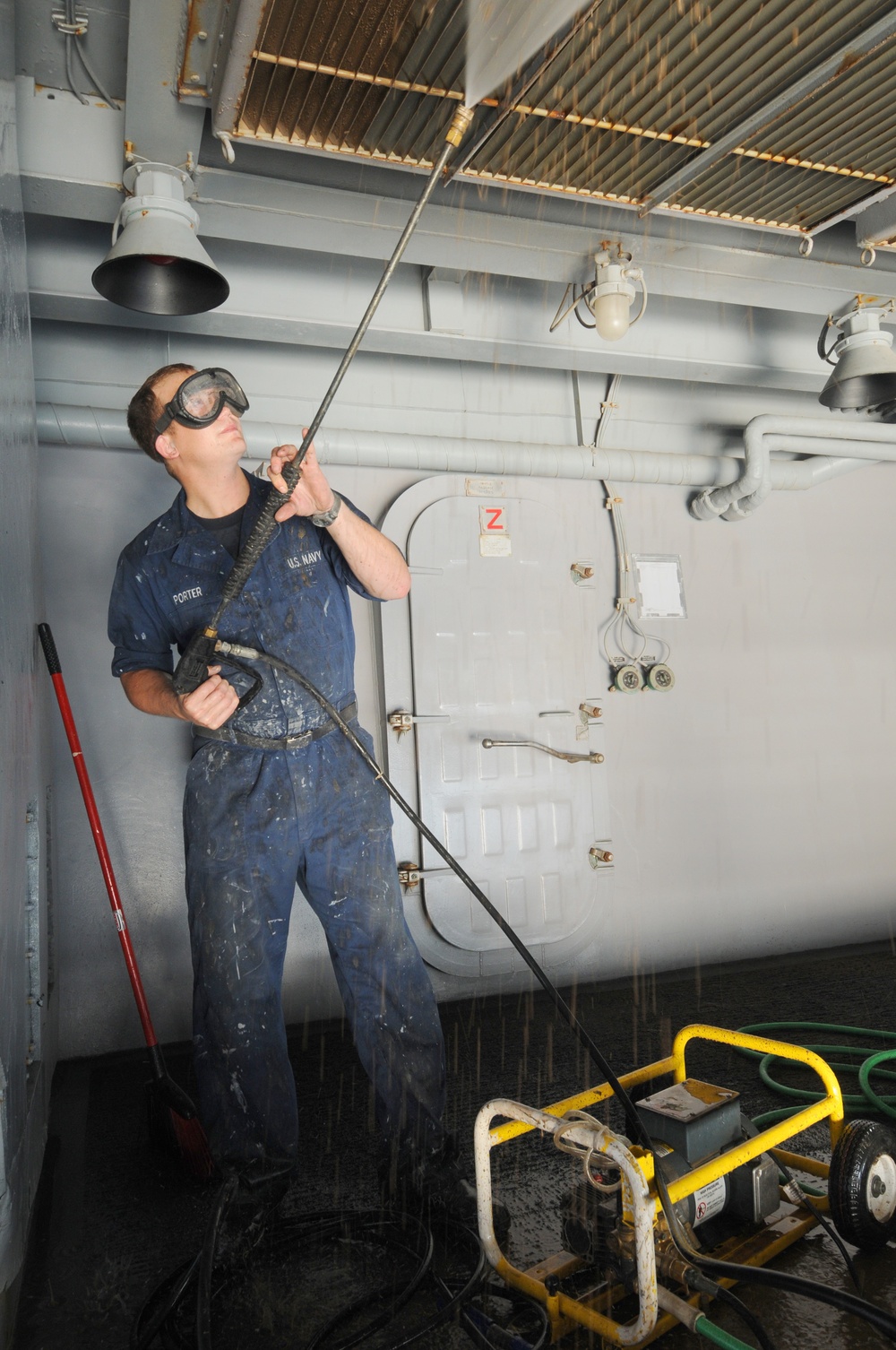 USS George H.W. Bush sailor pressure washes the overhead