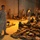 Military personnel in MARPAT (Marine pattern) camouflage uniforms stand among rows of gear and equipment laid out on the floor of what appears to be a large indoor facility or hangar. The scene resembles a gear inspection or pre-deployment equipment layout, commonly known as a 'layout' or 'inspection in ranks.' Multiple service members are standing at attention or observing the organized equipment spread across the floor.