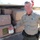 Operation Pipeline Express Drug Arrests A sheriff's deputy poses next to an open vehicle compartment packed with large wrapped bundles, consistent with a drug seizure. A second law enforcement officer in green tactical uniform is visible in the background. The scene appears to be a roadside stop in a desert environment.