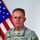 An official U.S. Army portrait of a senior non-commissioned officer wearing Army Combat Uniform (ACU) digital camouflage. The subject is posed in front of a U.S. flag with gold fringe, consistent with a formal military portrait setting. Rank insignia and name tape are visible on the uniform.