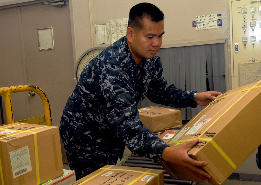 Volunteer sailor lifts a box at Fleet Activities Yokosuka post office