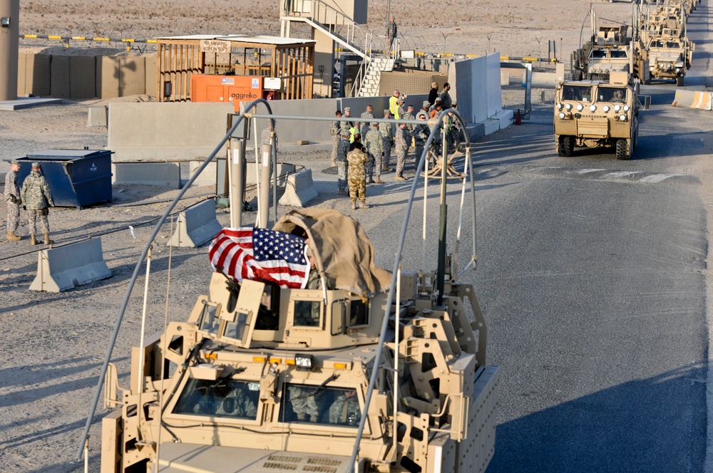 Last troops out of Iraq: Soldier holds American flag on convoy