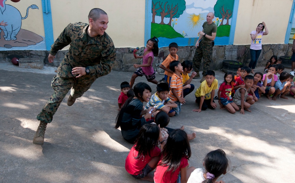 Marine plays with Cambodian children during community service project