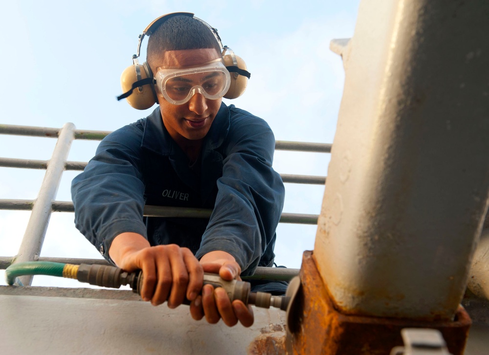 USS Cape St. George sailor removes rust