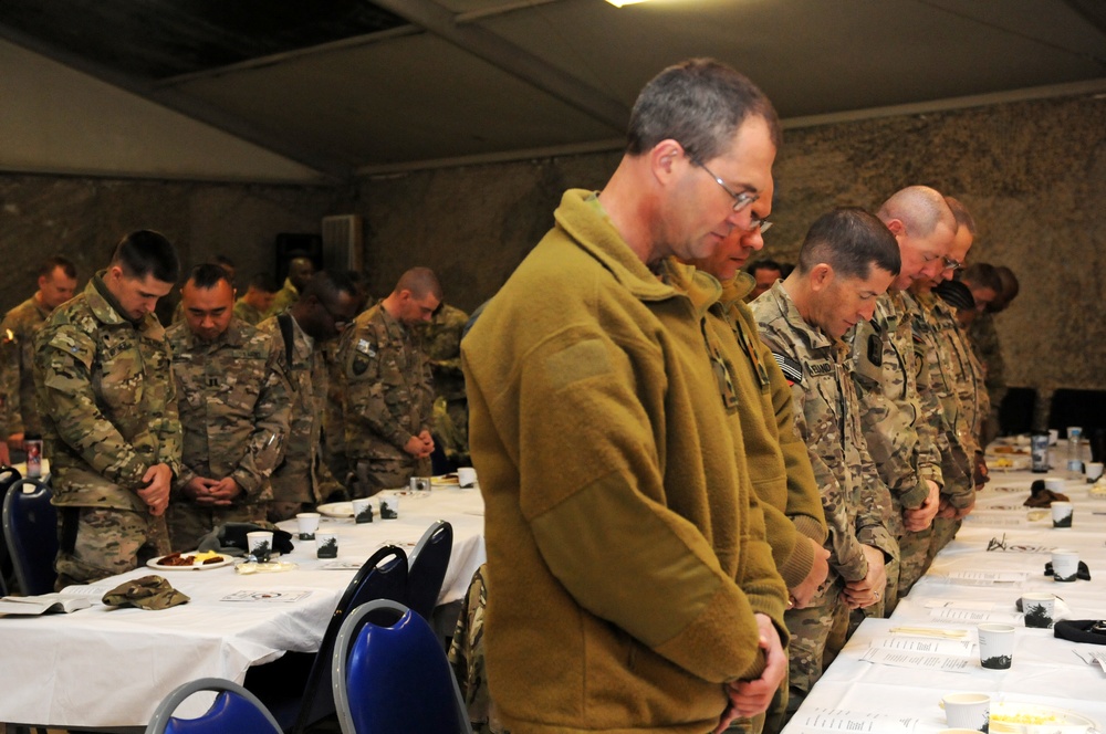 NATO service members bow their heads during the invocation at National Prayer Breakfast