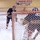 An ice hockey scene showing a player in a navy, black, and gold uniform approaching the goal, with a goaltender positioned in the crease. The game is taking place at a rink associated with 'The North Pole Patriots,' as indicated by a banner on the wall. Both players wear matching team colors, suggesting this may be a practice or intra-squad situation.
