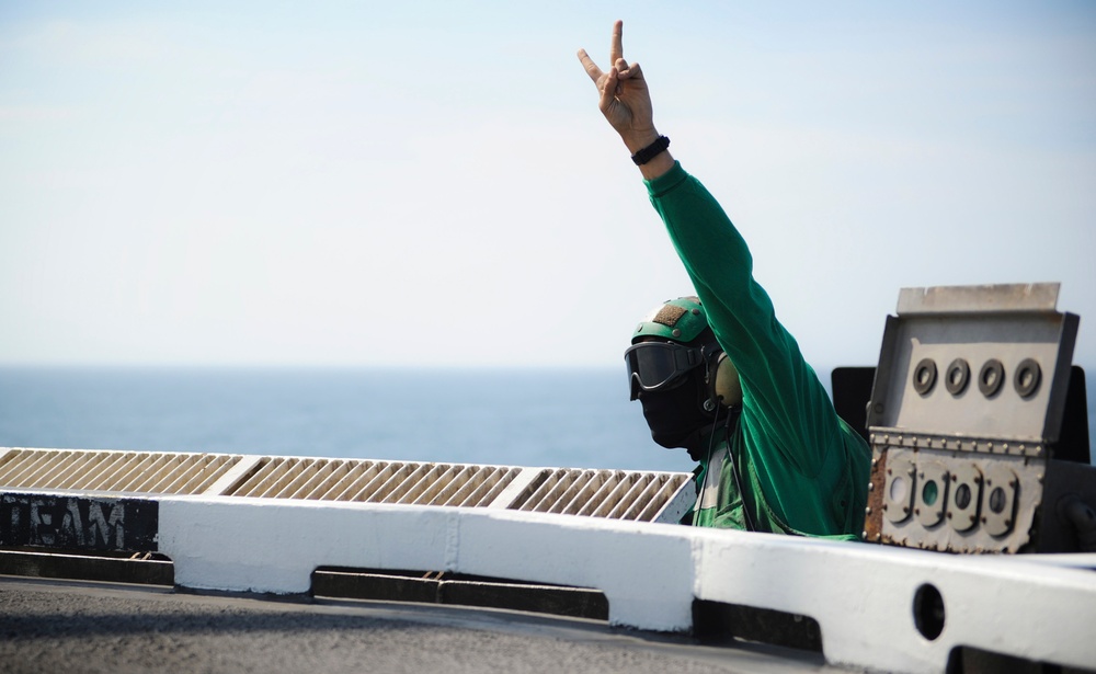 USS George H.W. Bush sailor signals pilot