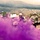 Big Island Military Police Training March 23-24 Military personnel in full combat gear are conducting what appears to be a training exercise in an arid, semi-mountainous terrain. Bright purple smoke grenades have been deployed, creating a dramatic visual screen around the soldiers and military vehicles. The scene includes multiple soldiers in ACU (Army Combat Uniform) pattern camouflage with tactical vests and helmets.