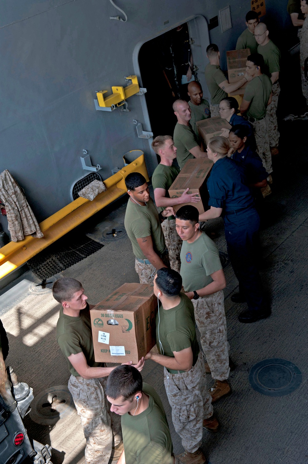 Sailors and Marines move supplies aboard USS Pearl Harbor