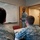 A military service member in Air Force ABU (Airman Battle Uniform) camouflage is conducting a briefing or training session in front of a whiteboard. Two other uniformed personnel are seated at a table facing the presenter. The whiteboard contains diagrams and text referencing locations including 'Ellsworth' and 'Rapid City,' suggesting aviation or operational planning content.