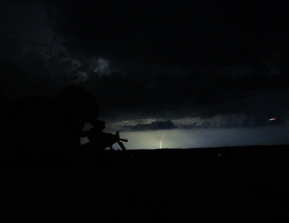 Indiana National Guard Spc. Seth Walker, silhouetted by a distant lightning strike