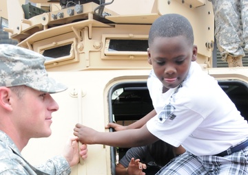 Field artillery soldiers showcase military vehicles for elementary students