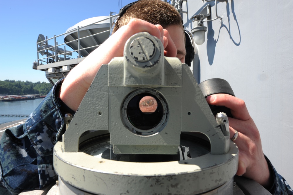 USS Nimitz sailor looks through telescopic alidade