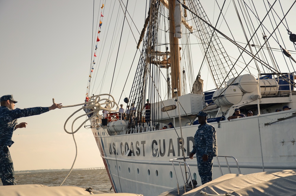 Navy Engineman 1st Class Sewel Baskett stands on the bow of a U.S. Naval Academy launch and passes a mooring line