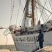 Navy Engineman 1st Class Sewel Baskett stands on the bow of a U.S. Naval Academy launch and passes a mooring line