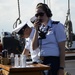 A Coast Guard Academy cadet, performing stern lookout watch duty, passes information into a sound powered telephone