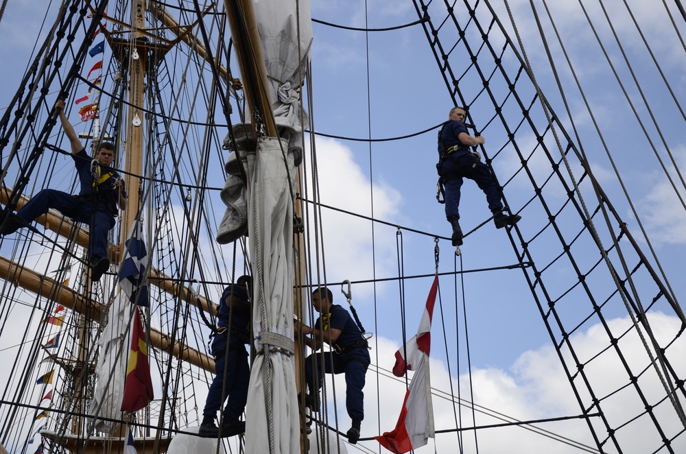 Coast Guardsmen work aloft above the deck aboard Coast Guard Barque Eagle