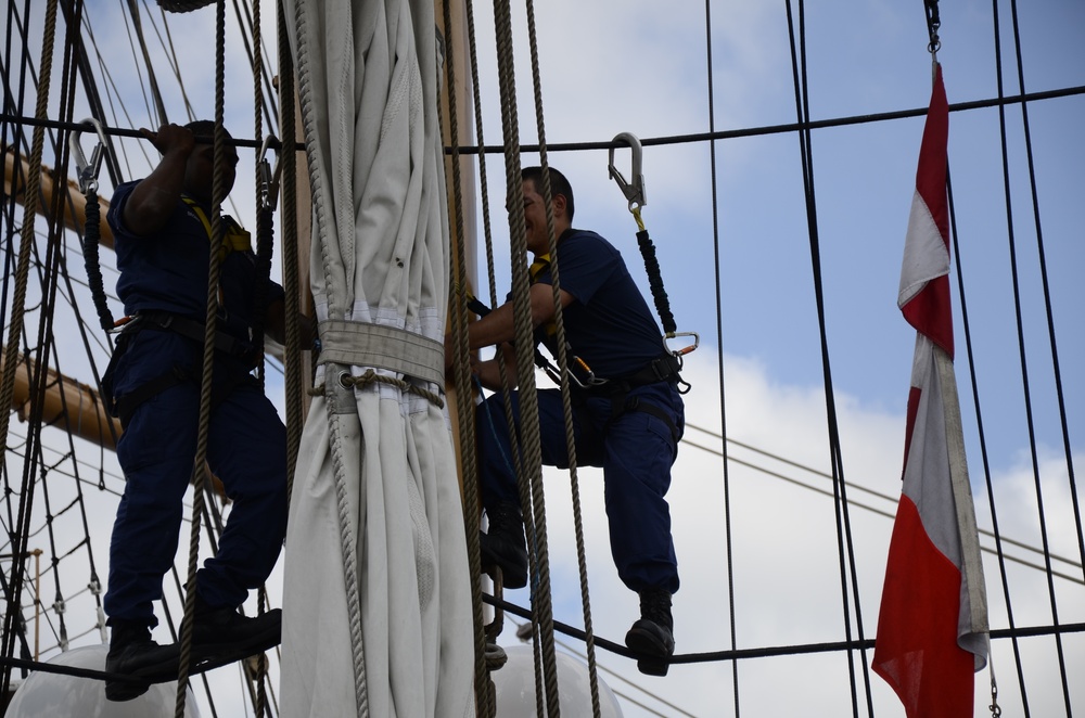 Coast Guardsmen work aloft above the deck aboard Coast Guard Barque Eagle