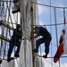 Coast Guardsmen work aloft above the deck aboard Coast Guard Barque Eagle