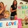 A group of family members, including children and adults, are gathered in what appears to be an indoor facility to welcome home a military or deployed father. A young boy holds a 'WE LOVE' sign while a girl in pink holds a colorful 'WELCOME HOME DAD!' sign. The atmosphere is celebratory, with adults clapping and cheering in the background.