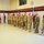 A military formation ceremony is taking place inside what appears to be a gymnasium or armory drill floor. A line of soldiers in Army Combat Uniforms (ACU/OCP pattern) stand at attention facing a single officer or NCO on the left, suggesting a formal inspection, award ceremony, or unit formation. American flags are displayed in the background alongside a 'Virtual Armory' banner.