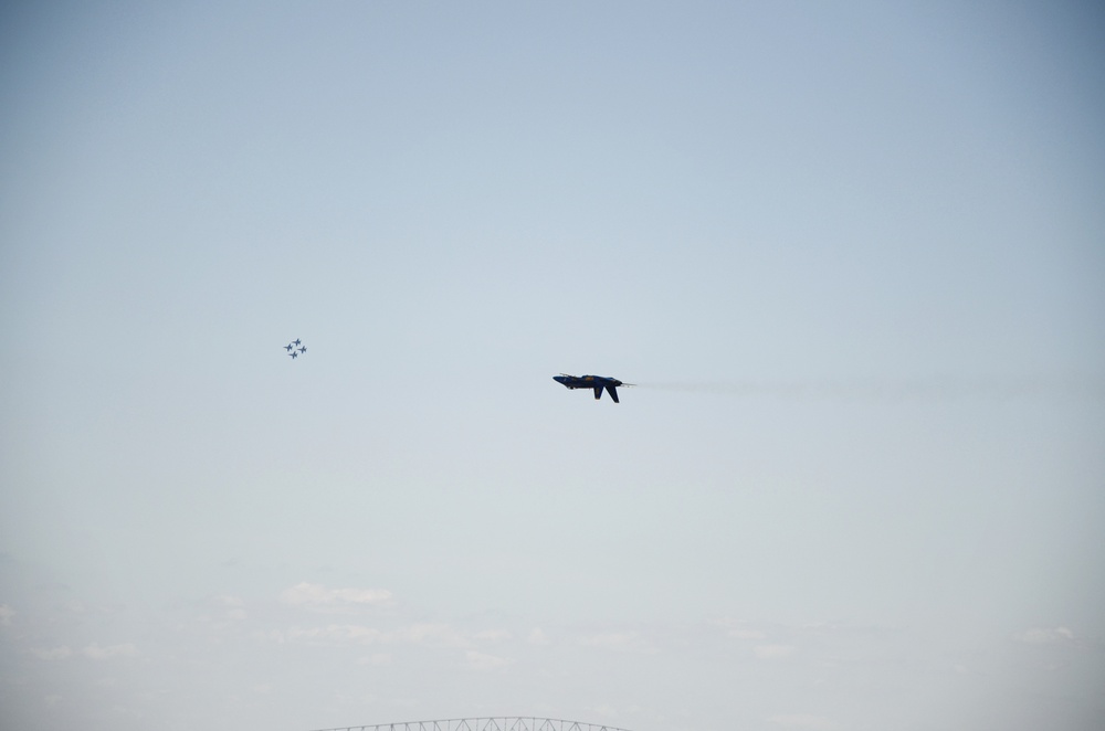 Blue Angel 5 flies inverted as it passes the U.S. Coast Guard Cutter Sledge (WLIC 75303) in Baltimore Harbor. Blue Angels 1, 2, 3 and 4 are to the left and the Francis Scott Key Bridge is below.