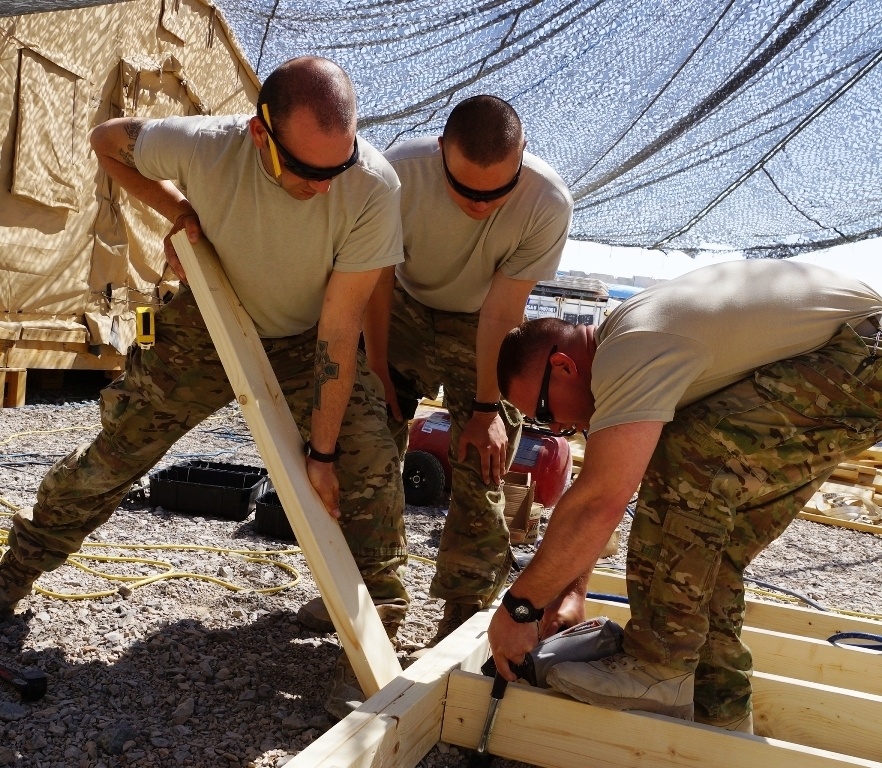 Soldiers work together to assemble a building frame in Afghanistan