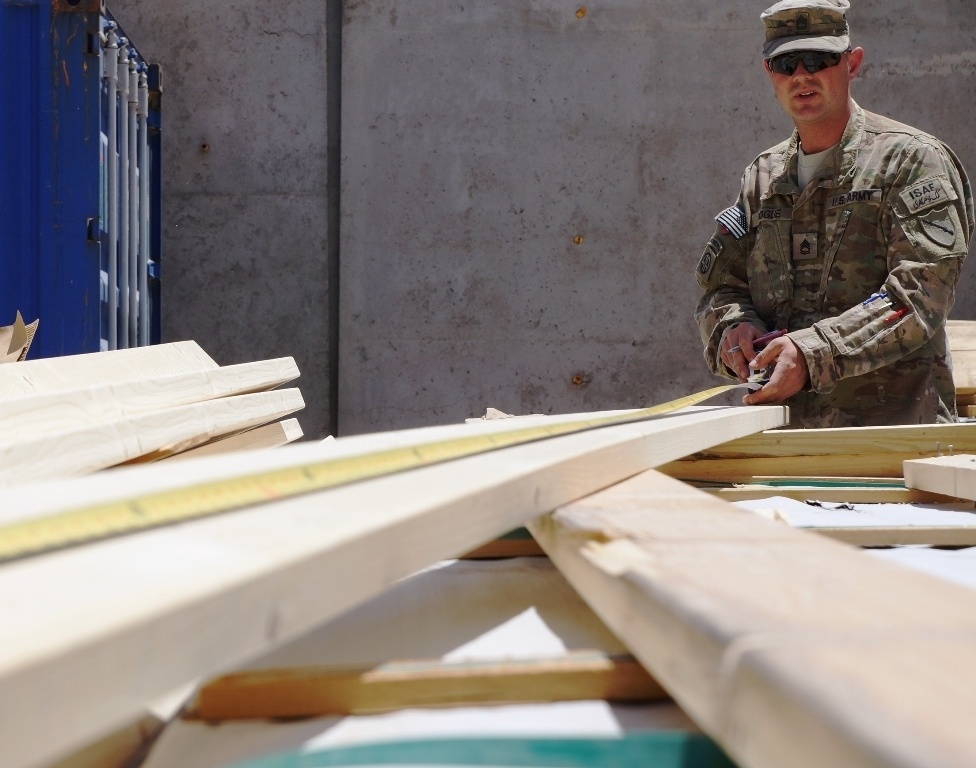 Soldier measures wood for a building in Afghanistan