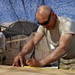 Kentucky soldier measures wood cuts for a building project in southern Afghanistan