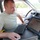 Patriot Exercise 2012 A man in a light green/olive t-shirt is seated in the driver's seat of a vehicle, operating a mounted touchscreen computer terminal with a keyboard and mouse. The vehicle appears to be a work or emergency services vehicle equipped with specialized computing and communication equipment. The setting suggests a mobile command or field operations context.