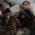 Patriot Exercise 2012 A group of military personnel in U.S. Air Force Airman Battle Uniform (ABU) camouflage pattern are gathered around boxes of MREs (Meals Ready to Eat) in what appears to be a warehouse or storage facility. They appear to be sorting, distributing, or inspecting the MRE packages. The scene suggests a logistics or supply operation, possibly during a training exercise or disaster relief effort.