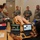 Patriot Exercise 2012 Military personnel in Air Force camouflage uniforms are conducting a medical simulation training exercise. A medical mannequin lies on a table connected to monitoring equipment, while trainees observe and take notes. Two laptops display vital sign monitoring software, and a person identified as 'Garza' operates the simulation controls.