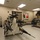 An indoor storage or maintenance room containing a wheeled cart loaded with multiple missile or rocket-like ordnance/training devices. The room also holds cylindrical tube-shaped objects on a separate rack to the right, along with general storage shelving and safety equipment on the walls. The space appears to be a professional facility, likely military, aerospace, or a museum storage area.