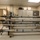 The image shows multiple missile or rocket assemblies stored horizontally on a wheeled metal rack inside what appears to be a military or aerospace facility. The projectiles are labeled with serial numbers including 'P50040N', 'P50245N', and 'NAVY PARALLEL', suggesting these are Navy-related ordnance or test articles. The room contains storage cabinets, a hazardous materials warning sign on the door, and general facility infrastructure.