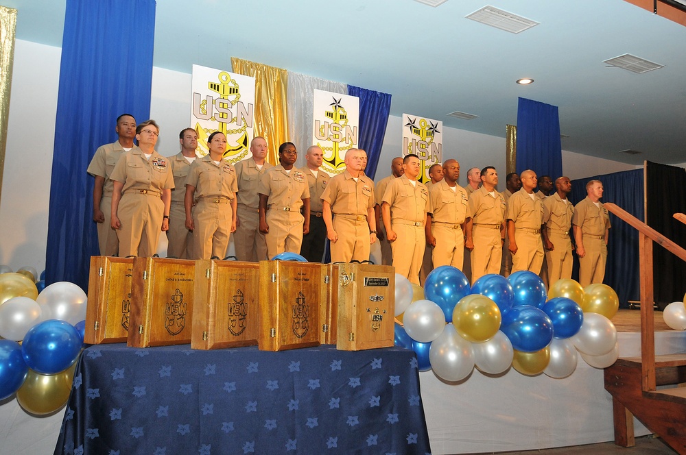 Chief petty officer selectees line up on stage in front of their shadow boxes during the chief petty officer’s pinning ceremony at Camp Lemonnier