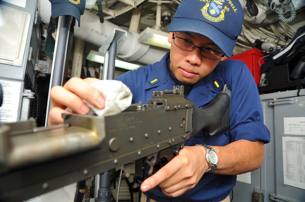 USS McCampbell sailor cleans machine gun