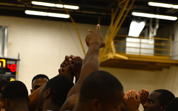 A basketball team is gathered in a huddle, raising their hands together in a team cheer or motivational moment. The players are wearing white uniforms with dark lettering, with visible names including 'KERSHAW' and partial text 'CANN' (likely 'CANNON'). A scoreboard in the background displays scores of 55 and 48 with 2:57 remaining.