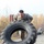 Arctic Wolves take a welcome break from the office A U.S. Army soldier in ACU (Army Combat Uniform) camouflage is performing a large tire flip exercise, a common military physical fitness training activity. The soldier is exerting significant effort pushing a large tractor-style tire forward. At least one additional soldier in uniform is visible in the background observing or resting.