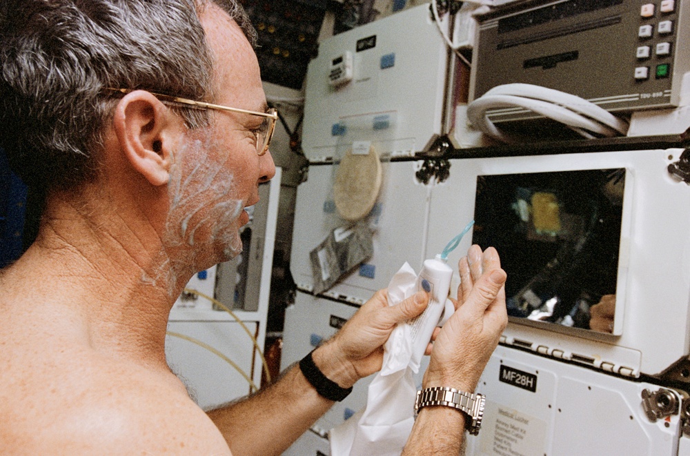 Commander Brian Duffy shaves in the middeck