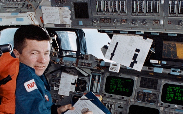 Crewmembers in the fwd flight deck reviewing inflight procedures manual.