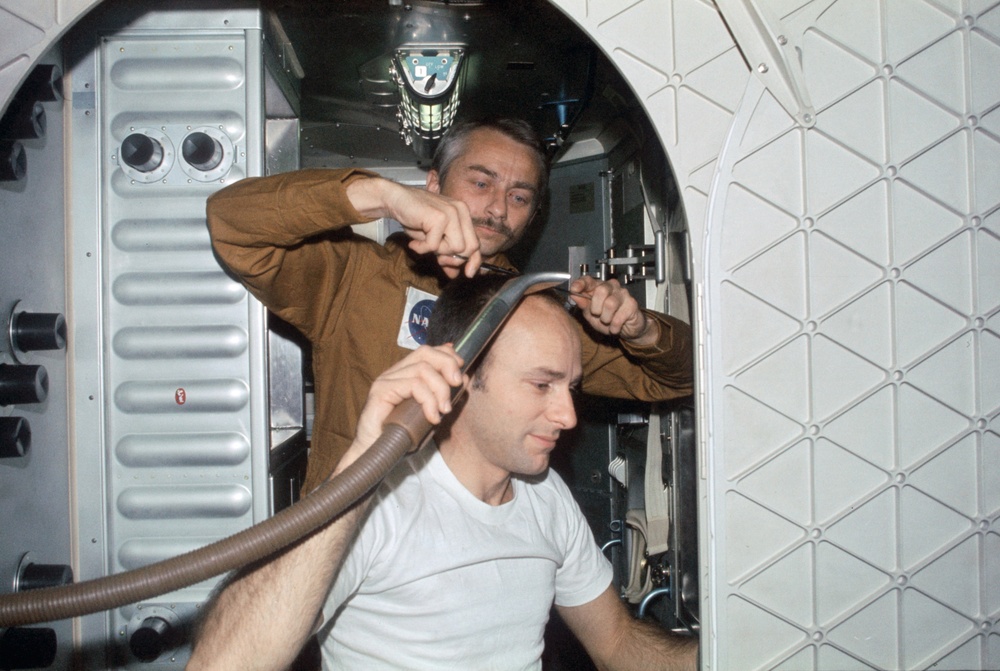 Astronaut Owen Garriott trims hair of Astronaut Alan Bean