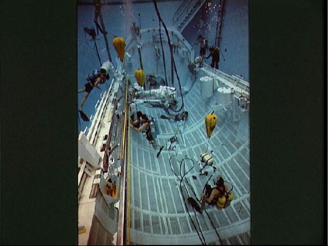 STS-37 crewmembers move CETA electrical cart along rail in JSC's WETF pool