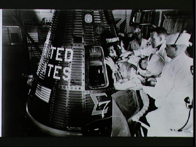 Astronaut Walter Schirra is assisted into his Sigma 7 spacecraft